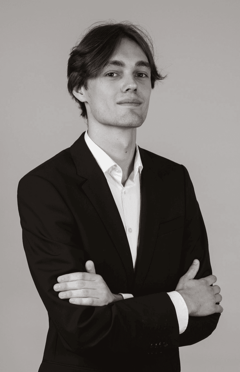 Confident man in a suit with arms crossed, black and white portrait.