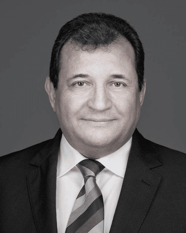 Man in a suit and tie with arms crossed, posed against a plain background.